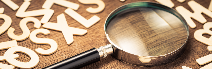 magnifying glass on a desk of scattered letters.